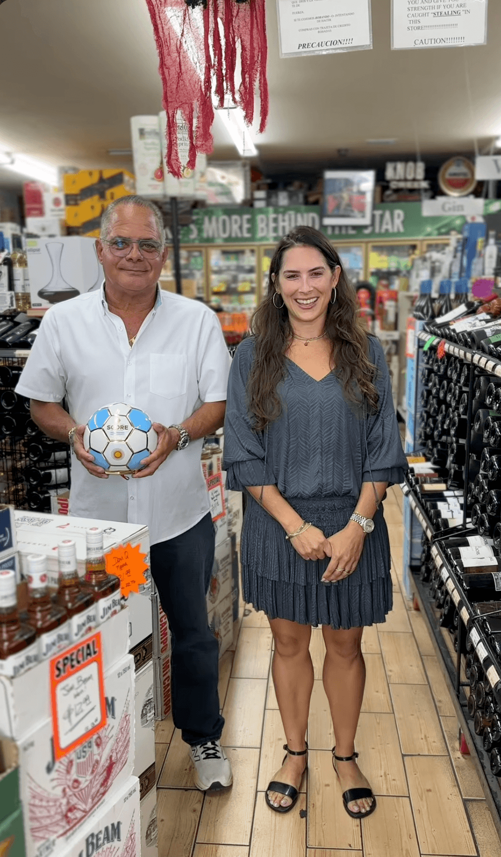 Two people smiling together among the wine and spirits shelves at Pantry Liquors 2